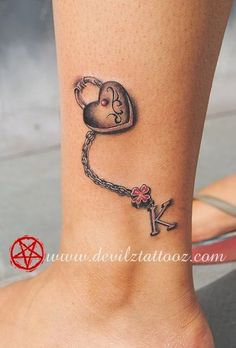 a small tattoo on the ankle of a woman with a heart and key attached to it