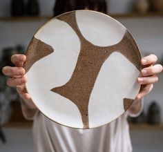 a woman holding up a brown and white plate