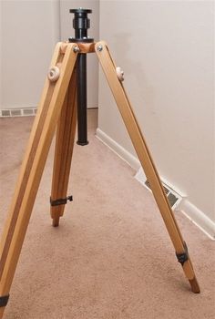 a wooden tripod stands on the floor in front of a white wall and door