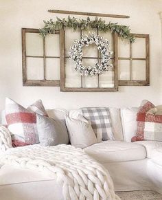 a living room filled with white furniture and christmas wreaths on the window sill