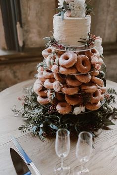 a wedding cake made out of doughnuts sits on a table with wine glasses