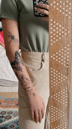 a woman with tattoos on her arm holding a cell phone