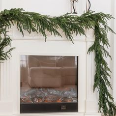 a fireplace decorated with christmas greenery and candles