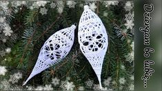 two white christmas ornaments hanging from a pine tree