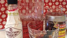 bottles and glasses filled with different types of condiments sitting on a counter top