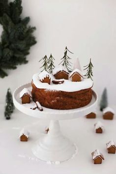 a cake with icing on top and small houses in the snow next to it