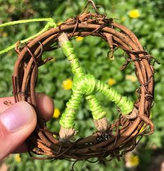 someone is holding up a wreath made out of twigs and twined with green string