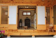 an open door to a wooden house with white shutters