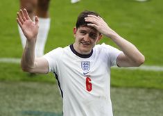 a man in white shirt holding his hands up to his head while standing on soccer field