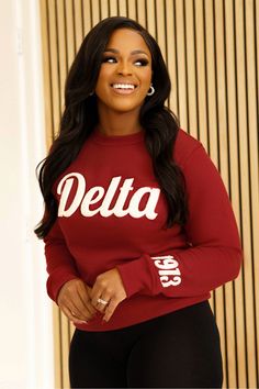 a woman wearing a red sweatshirt and black leggings, smiling at the camera