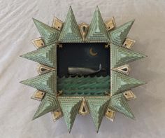 an ornate green and gold star shaped clock on a white sheeted surface with the moon in the sky