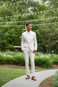 a man in a white suit standing on a sidewalk