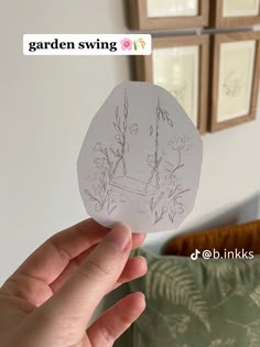 someone holding up a piece of paper with flowers drawn on it in front of a couch