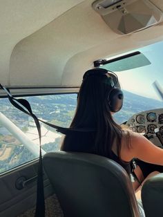 a woman sitting in the cockpit of an airplane with headphones on and looking out