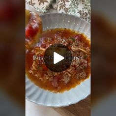 a white plate topped with pasta and meat covered in sauce next to a wooden cutting board