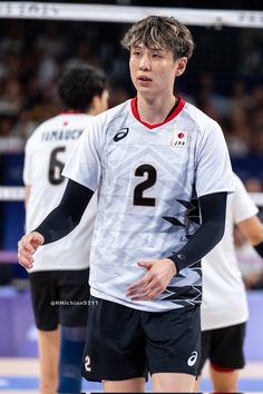 a young man standing on top of a volleyball court