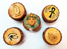 four cupcakes decorated with egyptian symbols