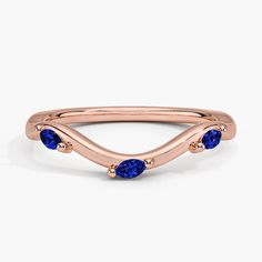 a rose gold ring with three blue sapphire stones on the side and an open band