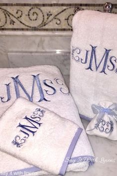 three personalized towels are sitting on the counter in front of a bathtub with blue ribbon