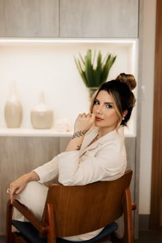 a woman sitting in a chair with her hand on her chin