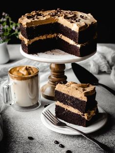 a chocolate cake on a plate with a slice cut out and coffee in the background