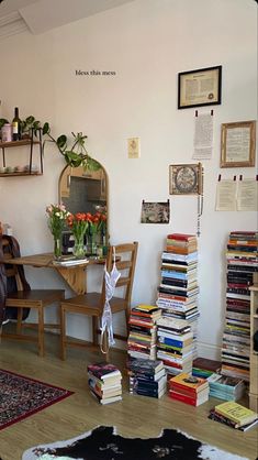 a living room filled with lots of books on top of a hard wood floor next to a wooden table