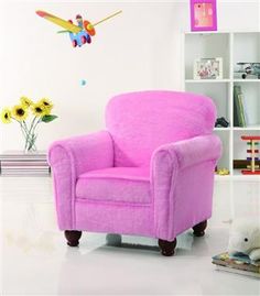 a pink chair sitting in front of a white wall with a clock on it's side