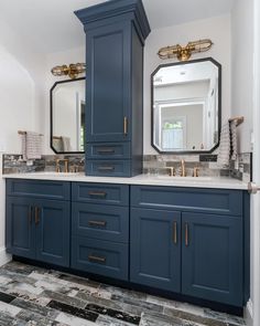 a large bathroom with blue cabinets and marble counter tops, two mirrors above the sinks