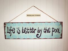 a sign hanging on the wall that says life's better by the pool,