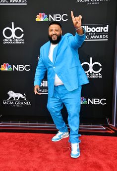 a man in a blue suit and white shirt on the red carpet at an awards event