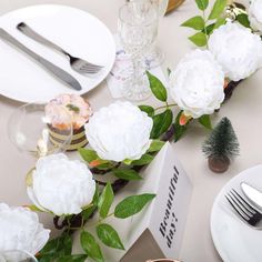 the table is set with white flowers and silverware