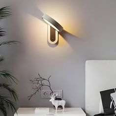 a white bed sitting next to a wall mounted light on the side of a wall