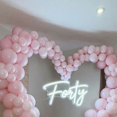 a heart shaped balloon frame with the word forty written on it in white and pink