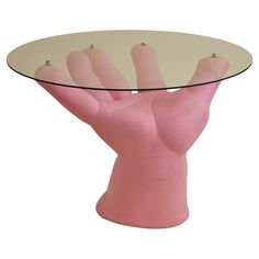 a pink plastic hand holding a glass table