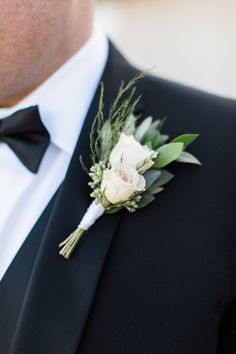 a man in a tuxedo wearing a boutonniere with white flowers