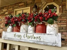 christmas decorations in mason jars are displayed on the front porch with holly and red berries