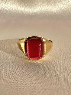 Antique 18k yellow gold ring from the United Kingdom. This signet ring features a vibrant synthetic ruby cabochon.  Great antique condition Size: 7.5 resizable** Weight: 3.5 grams Band: 11.1 mm (front), 1.7 mm (back) Synth Ruby: 8.3 mm x 10.0 mm  Hallmarks:18CT Please note, vintage and antique jewelry may come with imperfections commensurate of their age. To see more photos and videos of this piece, visit our Instagram: www.instagram.com/23carat PLEASE READ ALL POLICIES regarding shipping, returns, tax, etc Modern Gold Signet Ring With Cabochon, Formal Gold Cabochon Signet Ring, Heirloom Red Signet Ring With Polished Finish, Classic Red Ruby Ring, Oval Cabochon, Classic Red Ruby Ring With Oval Cabochon, Gold Ruby Ring Oval Cabochon With Polished Finish, Formal Red Domed Rings, Modern Yellow Gold Signet Ring With Cabochon, Classic Red Signet Ring For Formal Occasions