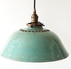 a green light hanging from a ceiling with a white wall in the backround