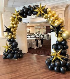 an arch made out of black and gold balloons with stars on it at a party