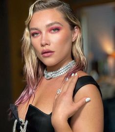 a woman with pink hair wearing a choker and diamond necklace, posing for the camera