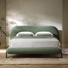 a green bed with white sheets and pillows