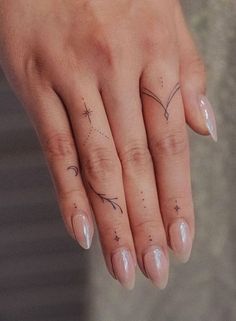 a woman's hand with two small stars on the middle finger and an arrow tattoo