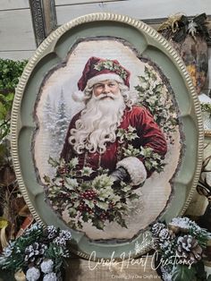 a plate with a santa clause on it and holly wreaths around the edge, in front of other christmas decorations