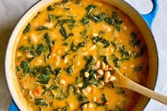 a pot filled with beans and spinach next to a wooden spoon