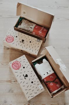 two opened boxes on top of a wooden floor filled with different types of wrapping paper