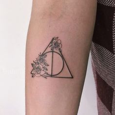 a tattoo on the arm of a woman with flowers and a deathly triangle in it