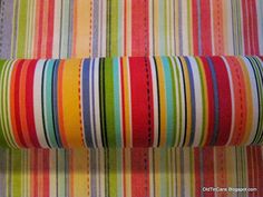 a roll of multicolored striped fabric sitting on top of a table next to a wall