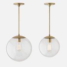 two clear glass globe pendant lights hanging from a brass finish ceiling fixture with one light on each side