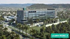 an aerial view of a large building with palm trees in the foreground and mountains in the background