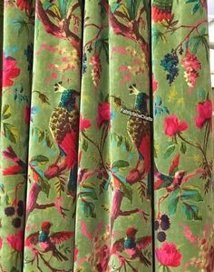 the curtain is decorated with colorful flowers and birds on green fabric, hanging from a rod